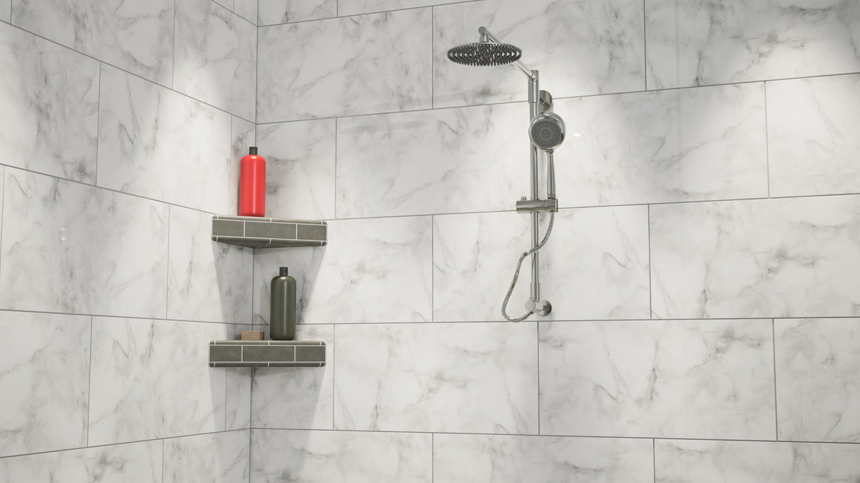 A wide view of a white-marbled standing shower with a rainfall shower head mounted on the wall next to an original corner shower shelf covered in gray tile while holding a red shampoo bottle, a gray conditioner bottle and a bar of soap.