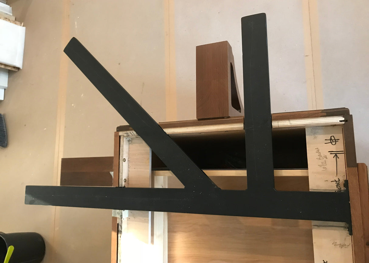 A Black Custom Support Bracket in a ‘K’ shape on a dark brown wooden countertop.