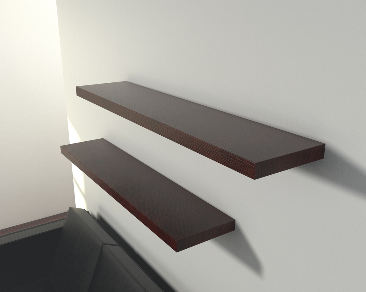 2 dark brown wooden floating shelves on a white wall above a black couch with a window in the background.