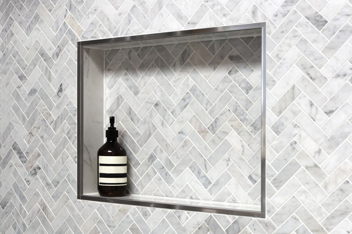 A medium show niche with a gray tile pattern holding a shampoo bottle.