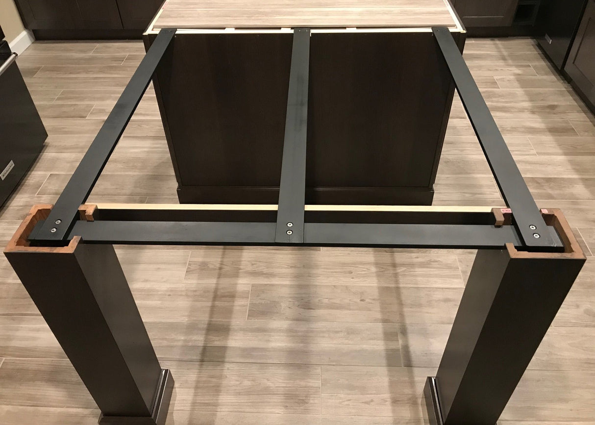 Squared-off Black Custom Support Brackets attached to a kitchen island with black column legs on a wooden floor.