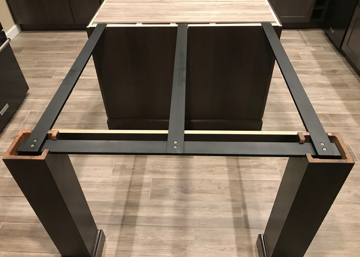 Squared-off Black Custom Support Brackets attached to a kitchen island with black column legs on a wooden floor.