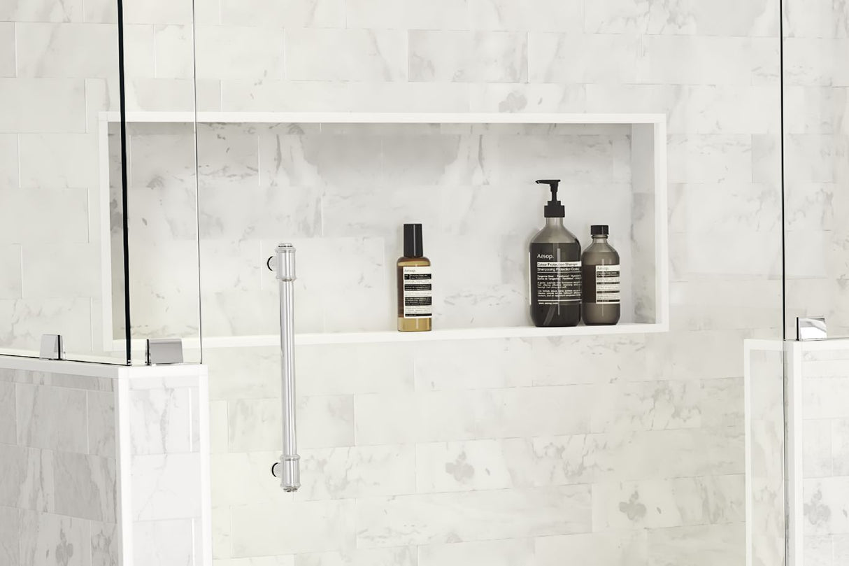 A standing shower with a large white marbled shower niche holding shampoo, conditioner and body wash bottles.