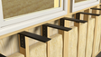 4 side wall free hanging shelf brackets affixed to an open wood wall beneath two white frame windows