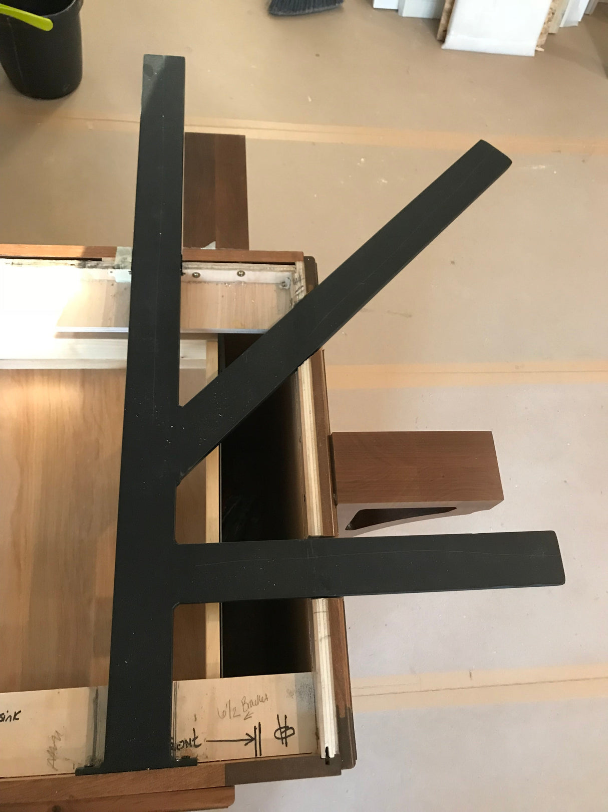 A Black Custom Support Bracket in a ‘K’ shape on a dark brown wooden countertop.