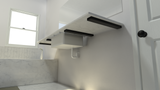 Underside view of the white marble floating bathroom countertop with 4 black Industrial Free Hanging Shelf Brackets attached to a white wall with a marble tub with a flower vase sitting on top with a single flower.